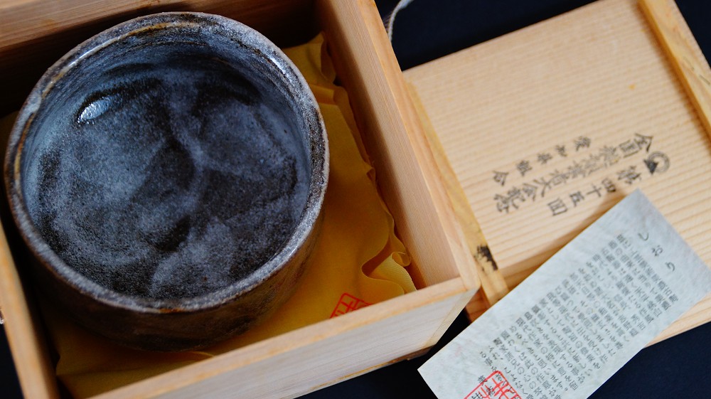 Chawan aus Shino-Keramik von Kazufumi Wada in der geoeffneten Aufbewahrungsbox neben dem Echtheitszertifikat