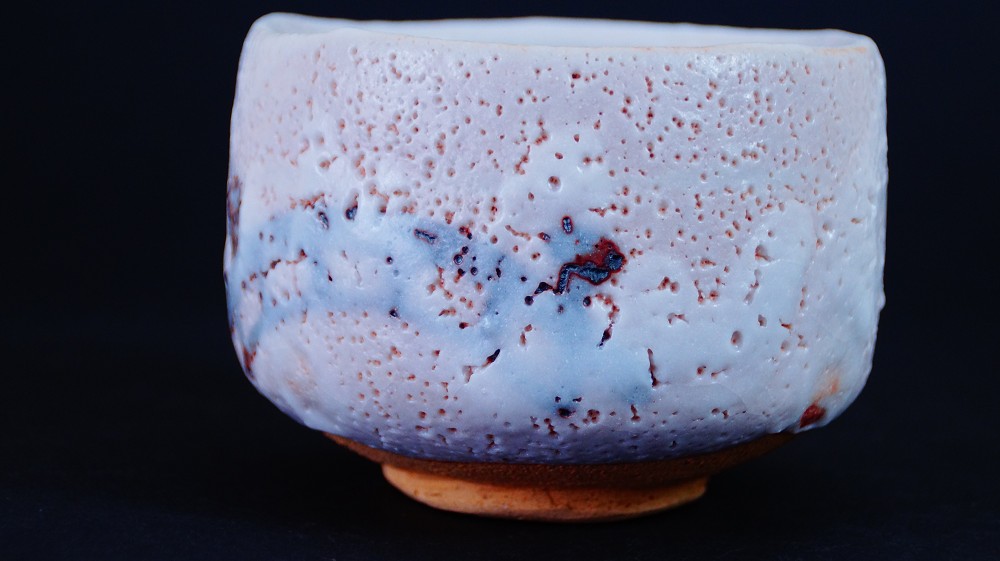 Seitenansicht der Chawan aus Shino-Keramik von Jyuzo Sato neben der beschrifteten Aufbewahrungsbox