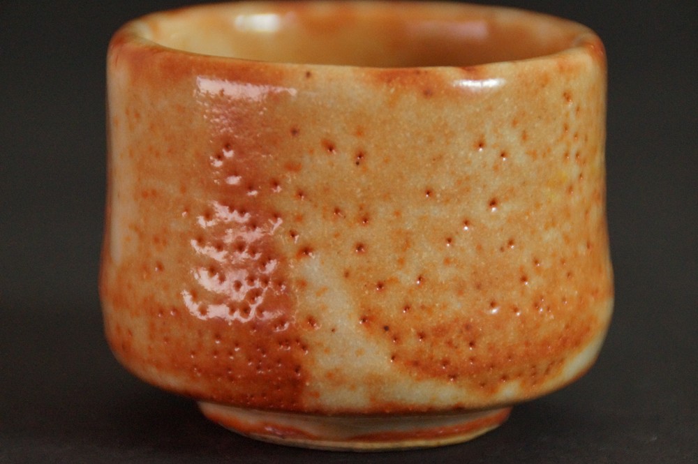 Seitenansicht des Guinomi mit warm orangefarbener Shino-Glasur ohne Bluetenmotiv