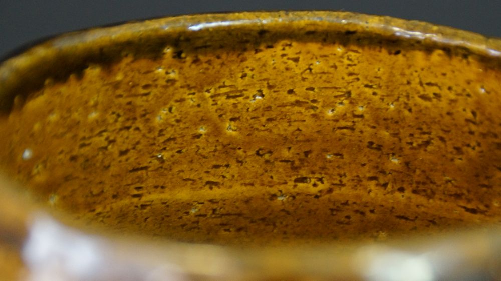 Nahaufnahme der genarbten honigfarbenen Innenglasur der Chawan aus Raku-Keramik