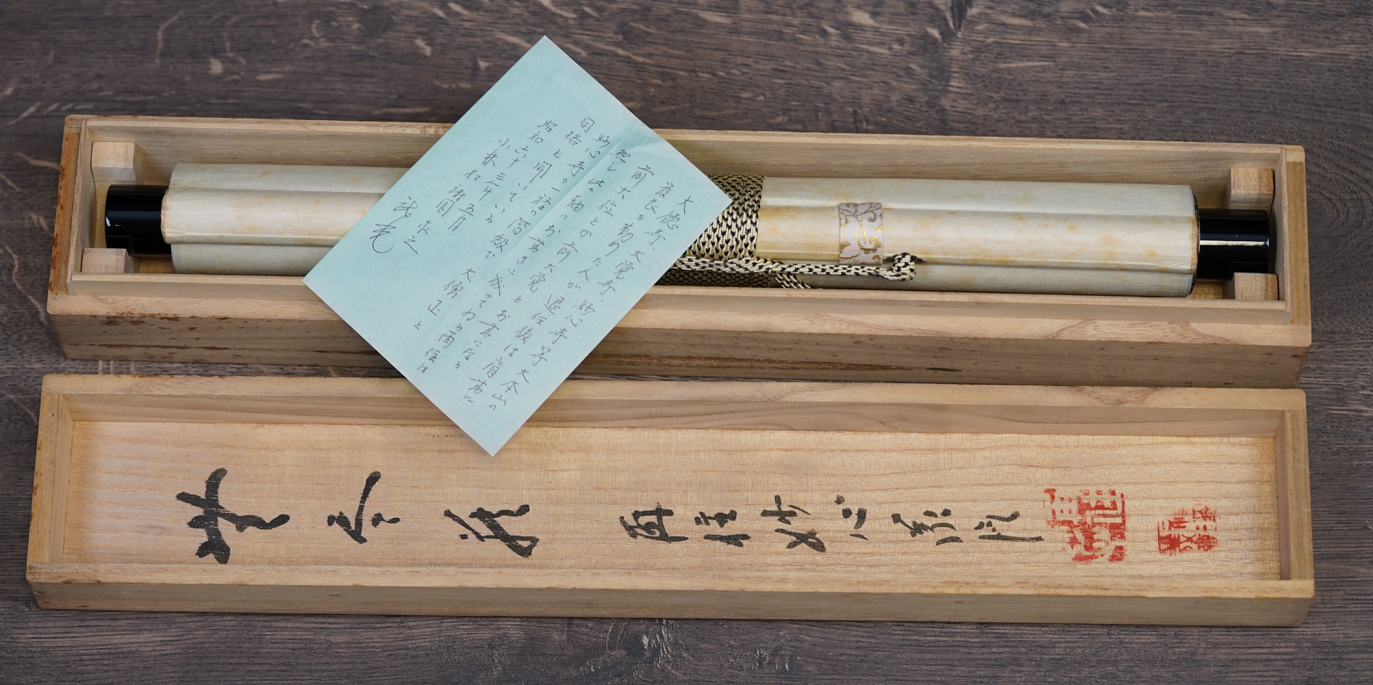 Geöffnete Aufbewahrungsbox mit zusammengerolltem Kakemono und handschriftlichem Begleitzettel