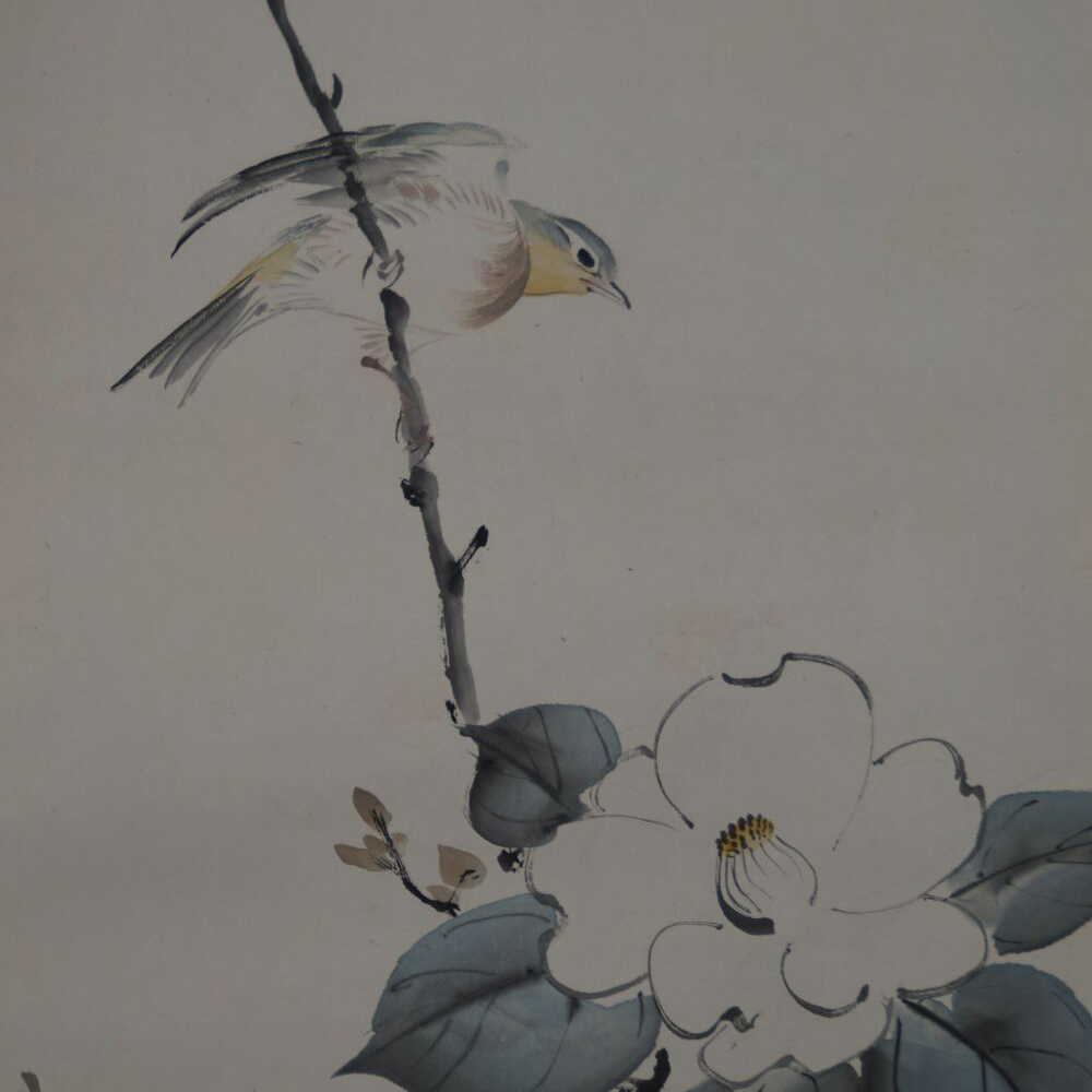 Nahaufnahme des Singvogels und der weissen Kamelienbluete im Kakemono