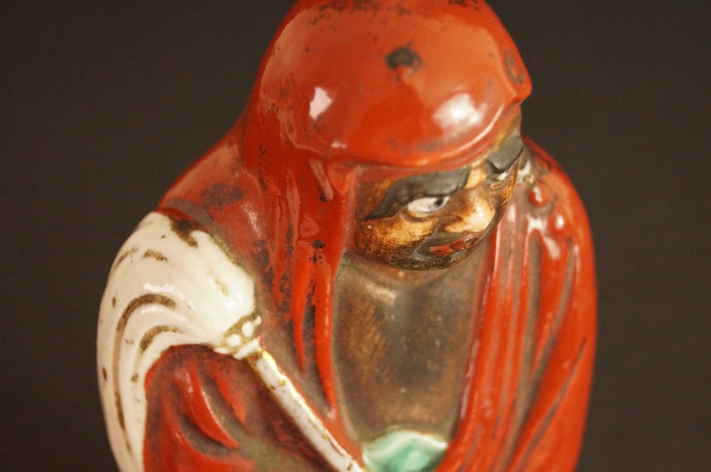 Bodhidharma Daruma Figur aus rotem Kutani-Porzellan Nahaufnahme von Gesicht und Kapuze von oben Motiv Nahaufnahme 2