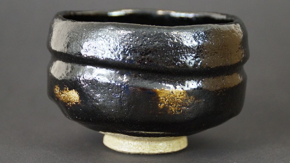Weitere Ansicht der Chawan Teeschale aus Raku-Keramik mit umlaufender Doppelrille und goldfarbenen Glasurflecken