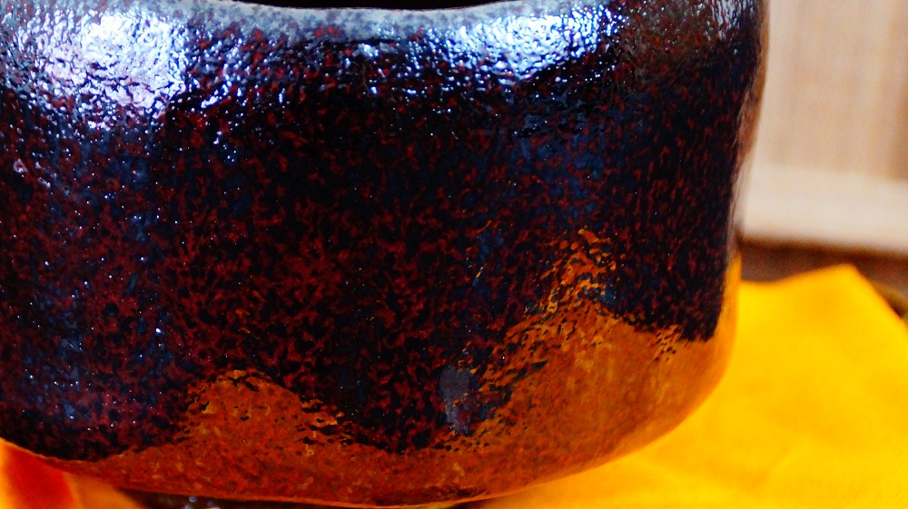 Nahaufnahme der rauen rotbraun-schwarz melierten Glasur der Chawan aus Raku-Keramik von Shoraku Sasaki