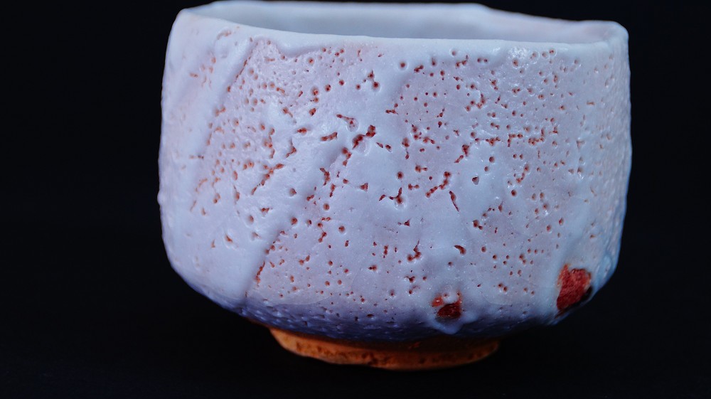 Weitere Seitenansicht der Chawan aus Shino-Keramik von Jyuzo Sato mit craquelierter Glasur und roten Feuerspuren