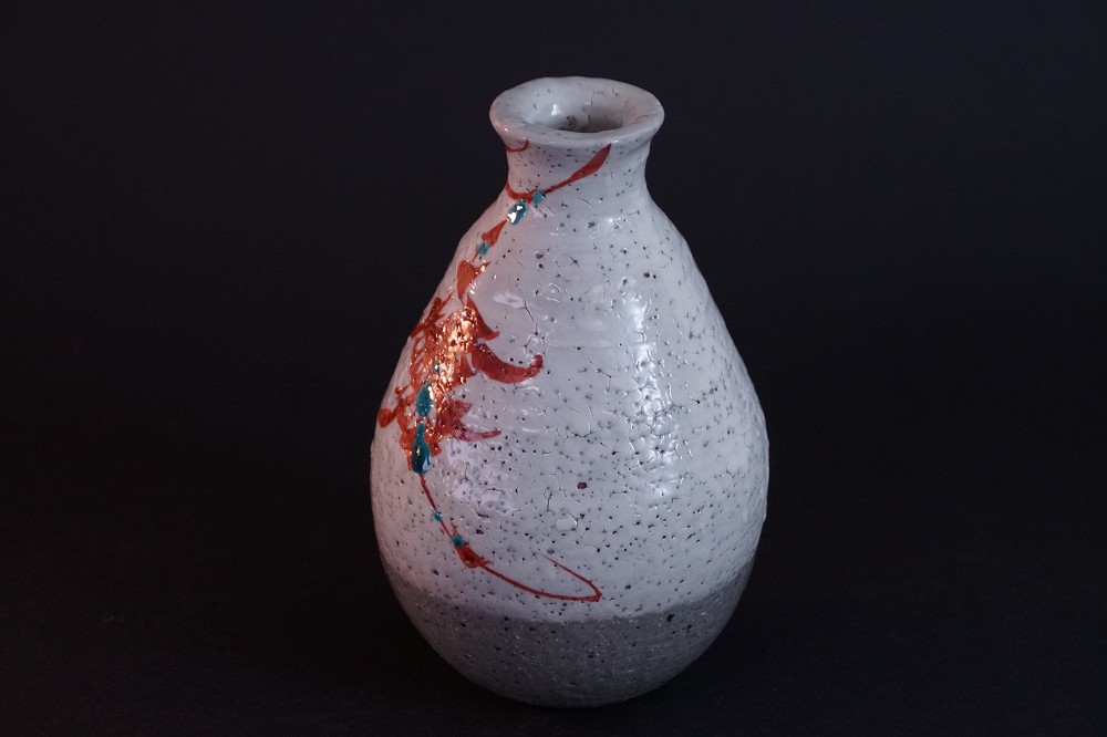 Frontalansicht der handgetoepferten Kyo Sake Flasche mit rotem Vogelmotiv