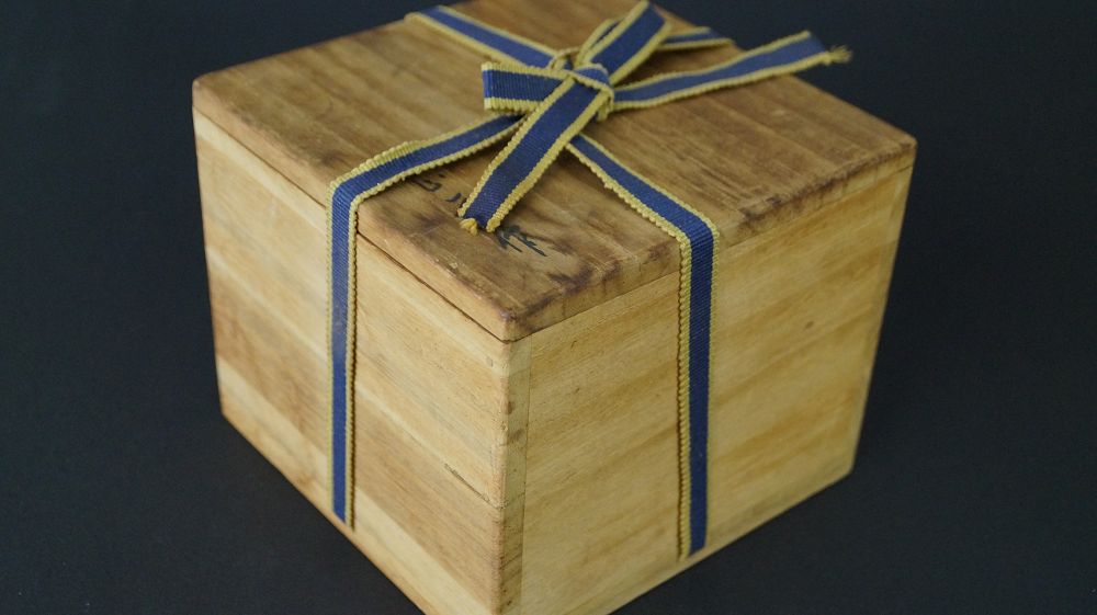 Geschlossene, mit blauem Band verschnuerte Aufbewahrungsbox der Chawan Teeschale aus Raku-Keramik