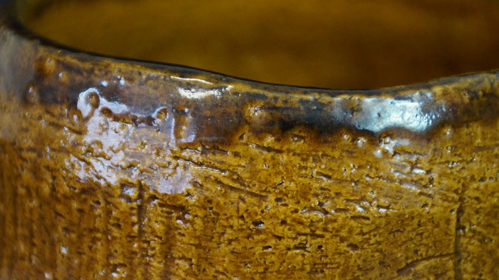 Nahaufnahme des dunkel gesprenkelten Randes der Chawan aus Raku-Keramik