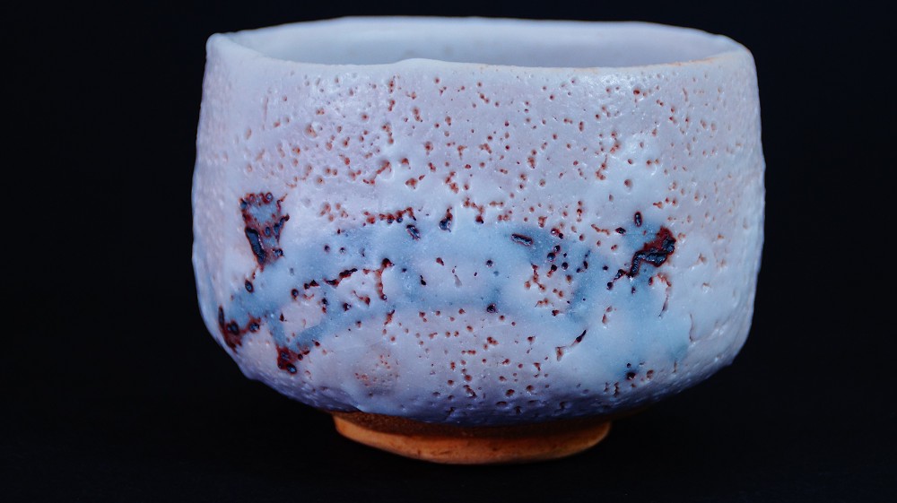 Chawan aus Shino-Keramik von Jyuzo Sato in der Frontalansicht mit weisslich-lavendelfarbener Glasur und rotem Feuerspurband