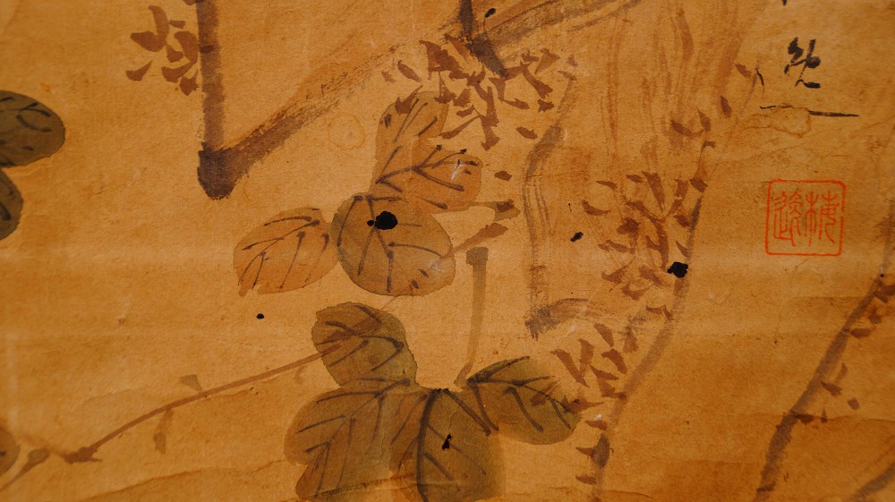 Nahaufnahme der Kuenstlersignatur und des roten Siegels neben den Chrysanthemenblaettern im Kakemono Reiher auf Fels mit Chrysanthemen von Yamamoto Baiitsu