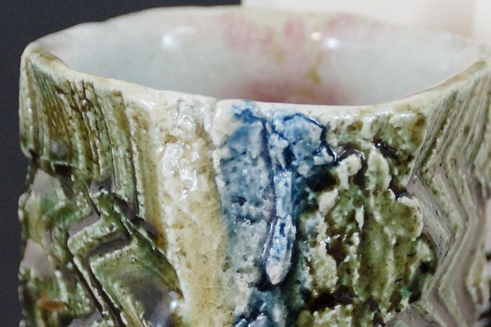 Rand und weiße Innenglasur eines japanischen Yunomi aus Oribe-Keramik mit grüner Glasur und reliefierter Wandung