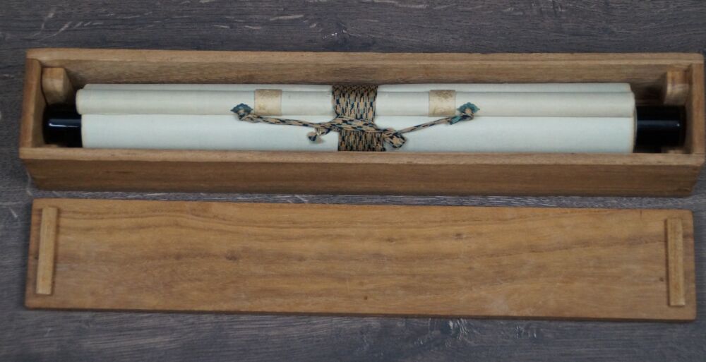 Opened storage box with rolled-up kakemono puppy in the evening glow beneath pines