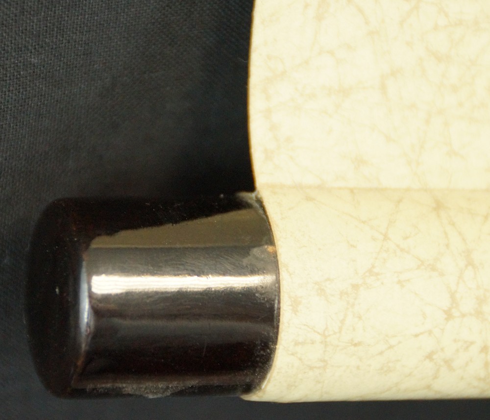 Close-up of the dark lacquered jikusaki at the end of the scroll roller
