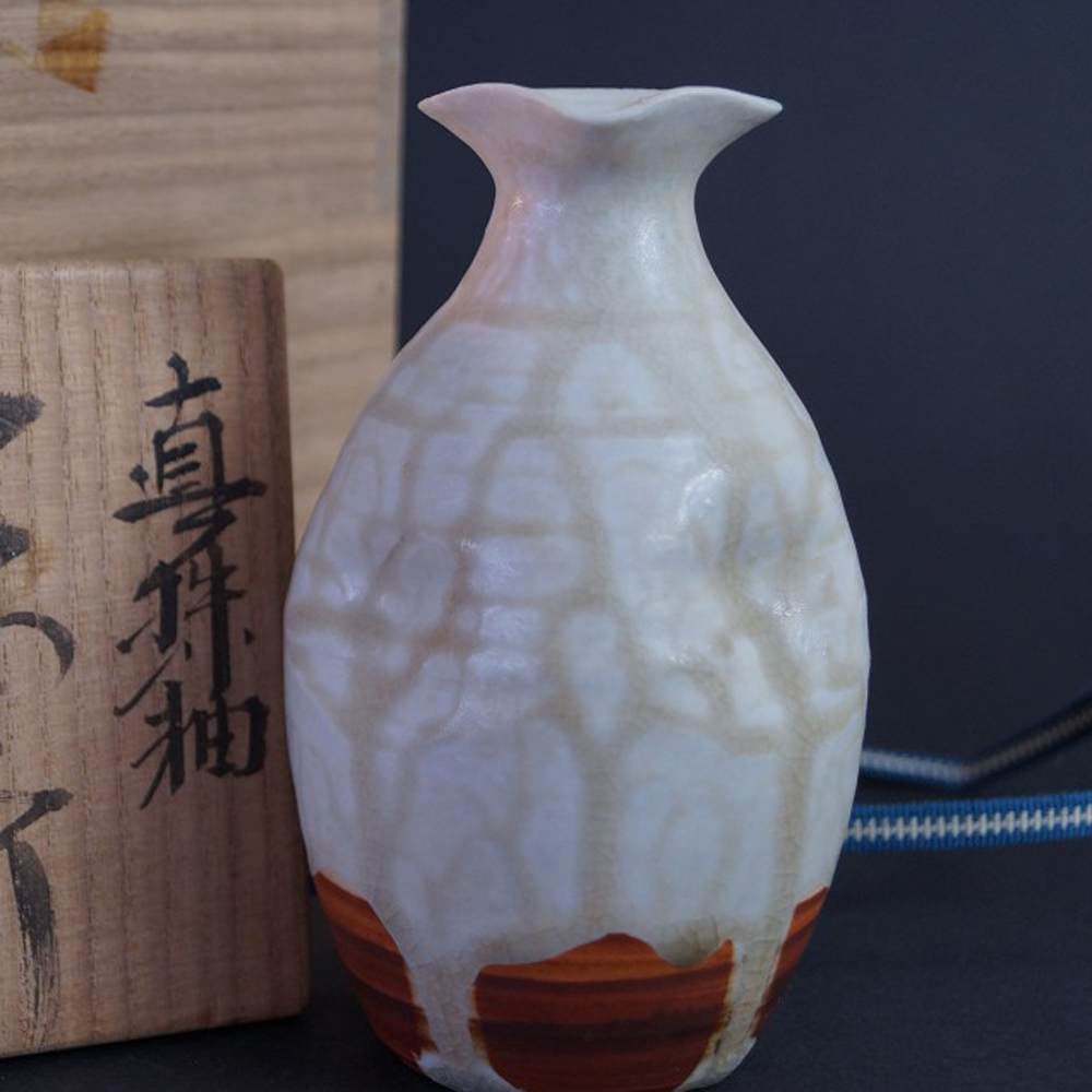 Vorschau-Nahaufnahme der Sake Flasche mit Aufbewahrungsbox im Hintergrund