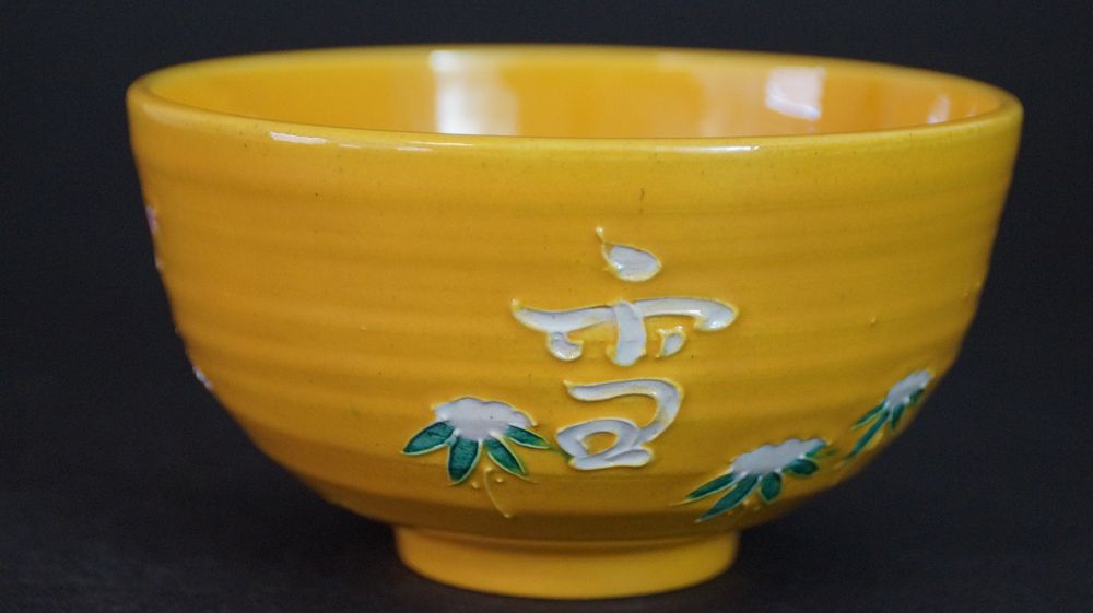 Weitere Ansicht der Chawan aus Kyoto-Keramik mit weiss aufgetragenem Schriftzeichen und Chrysanthemenmotiv