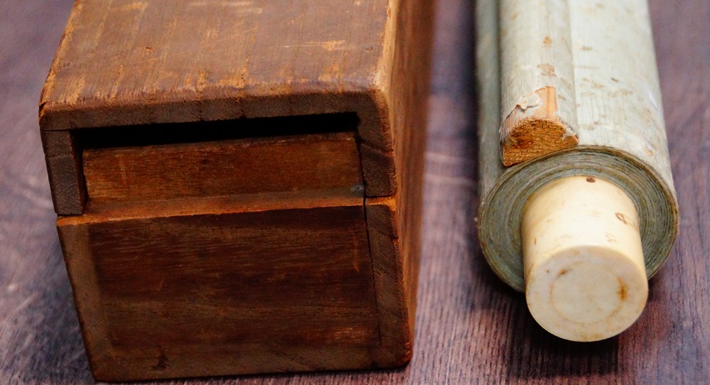 Kakemono von Nishioka Sosen mit Elfenbein-Rollenenden, teilweise aus der hoelzernen Aufbewahrungsbox gezogen