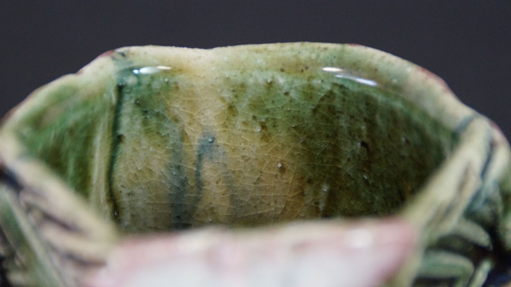 Nahaufnahme der craquelierten gruen-gelben Innenglasur der Guinomi Sake-Schale aus Oribe-Keramik