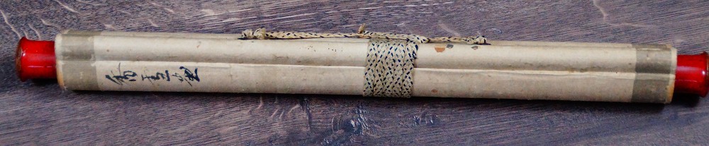 Zusammengerolltes Kakemono mit Kordelverschnuerung und roten Rollenenden