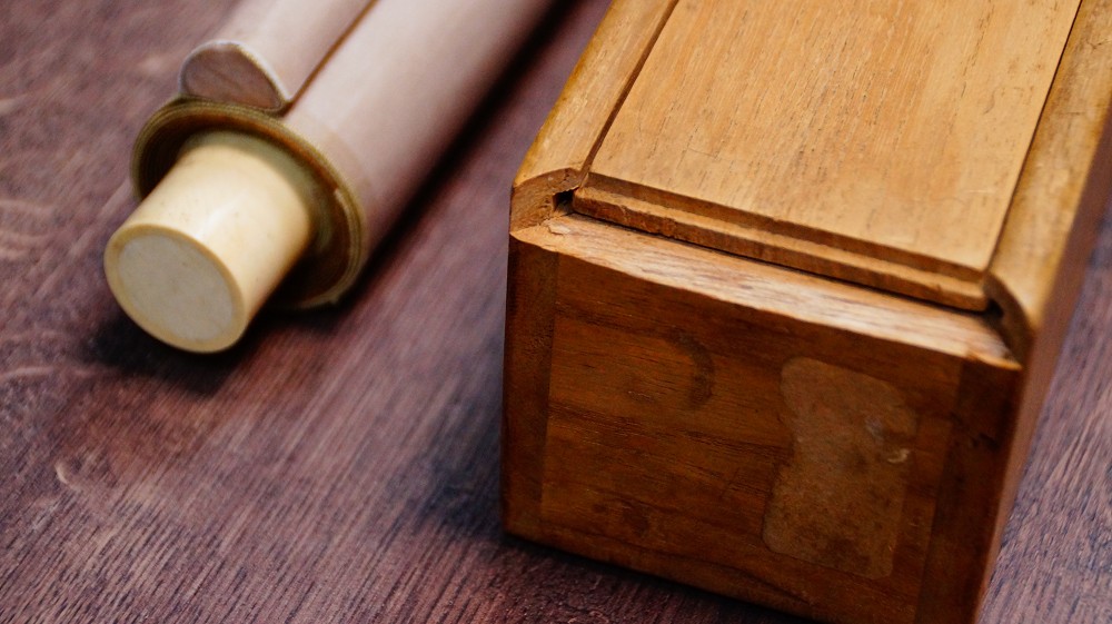 Kakemono mit Elfenbein-Rollenenden neben der geoeffneten hoelzernen Aufbewahrungsbox