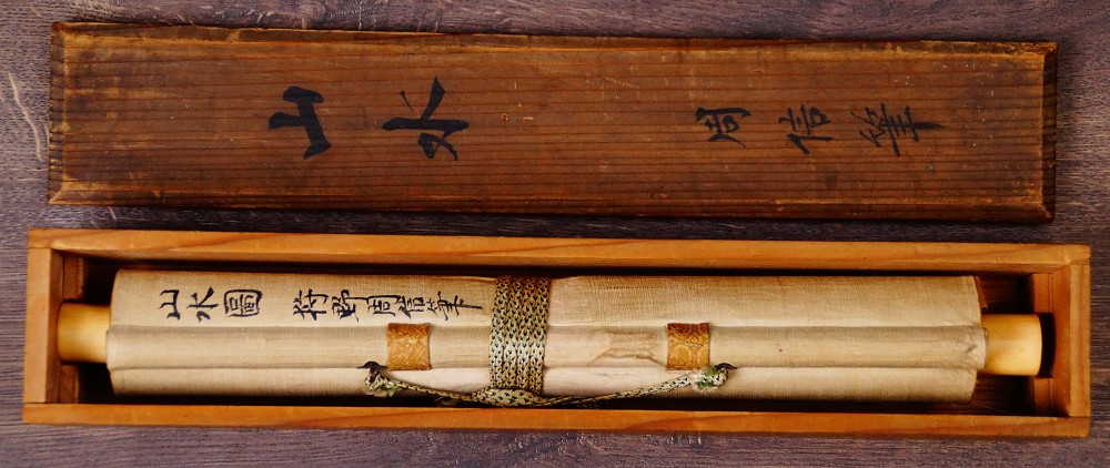 Zusammengerolltes Kakemono von Kano Shushin mit Verschnuerung und Beschriftung neben der geoeffneten Aufbewahrungsbox