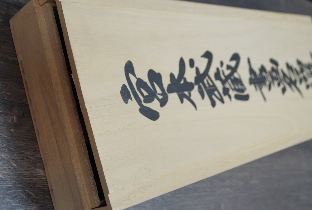 Nahaufnahme des Holzdeckels mit Tuschebeschriftung der Aufbewahrungsbox der Triptychon-Drucke nach Miyamoto Musashi