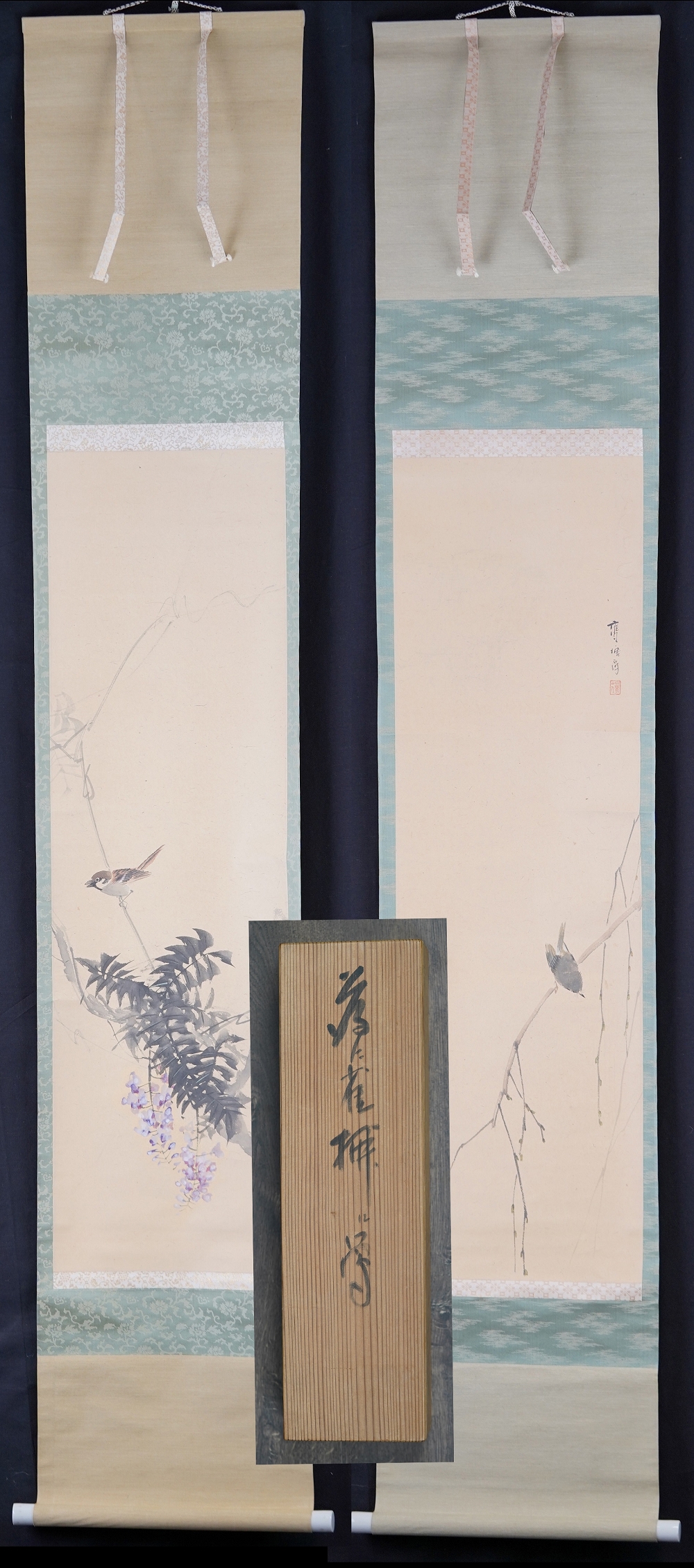 Further view of both hanging scrolls of the set side by side with the lid of the storage box