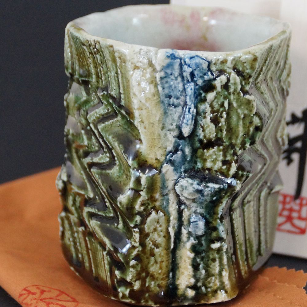 Yunomi Tee-Schale aus Oribe-Keramik von Kawachi Hidetoshi in der Gesamtansicht mit gruener Glasur und Zickzackmuster