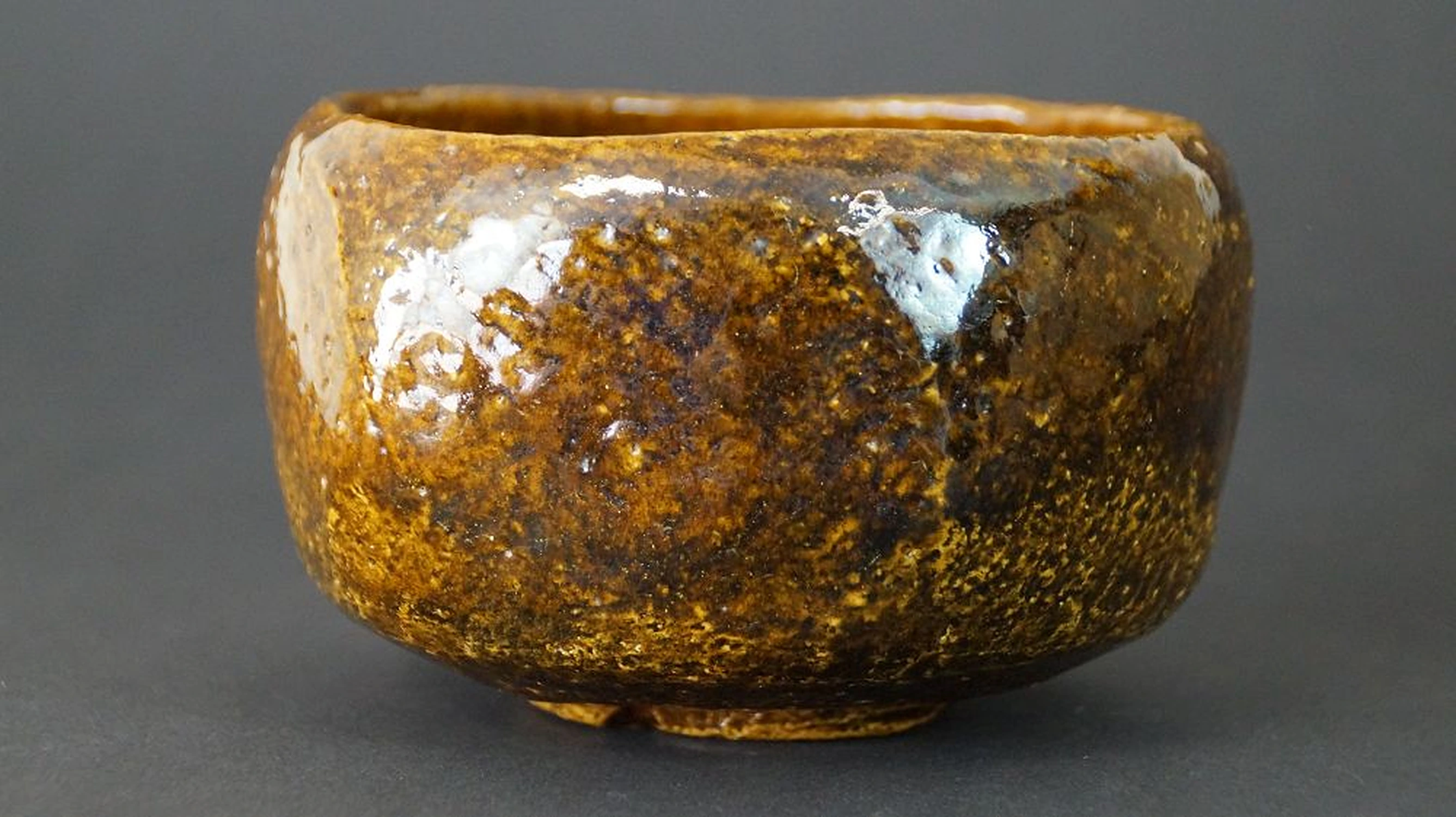 Otra vista del cuenco de té chawan de cerámica Ōhi con superficie de esmalte moteado