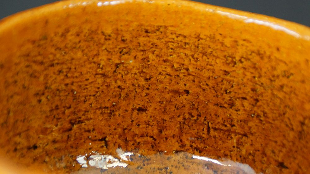 Extreme Nahaufnahme der gesprenkelten orangefarbenen Glasurstruktur der Chawan Teeschale aus Ohi-Keramik