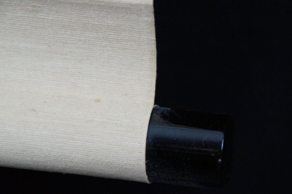 Detail view of the black lacquered scroll end with cream-colored silk of the hanging scroll Puppy in the Evening Glow Under Pines
