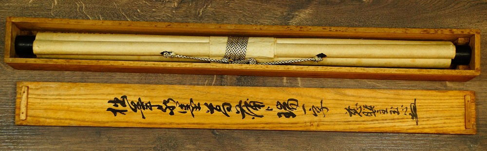 Zusammengerolltes Kakemono in der geoeffneten Holzbox neben dem beschrifteten Deckel